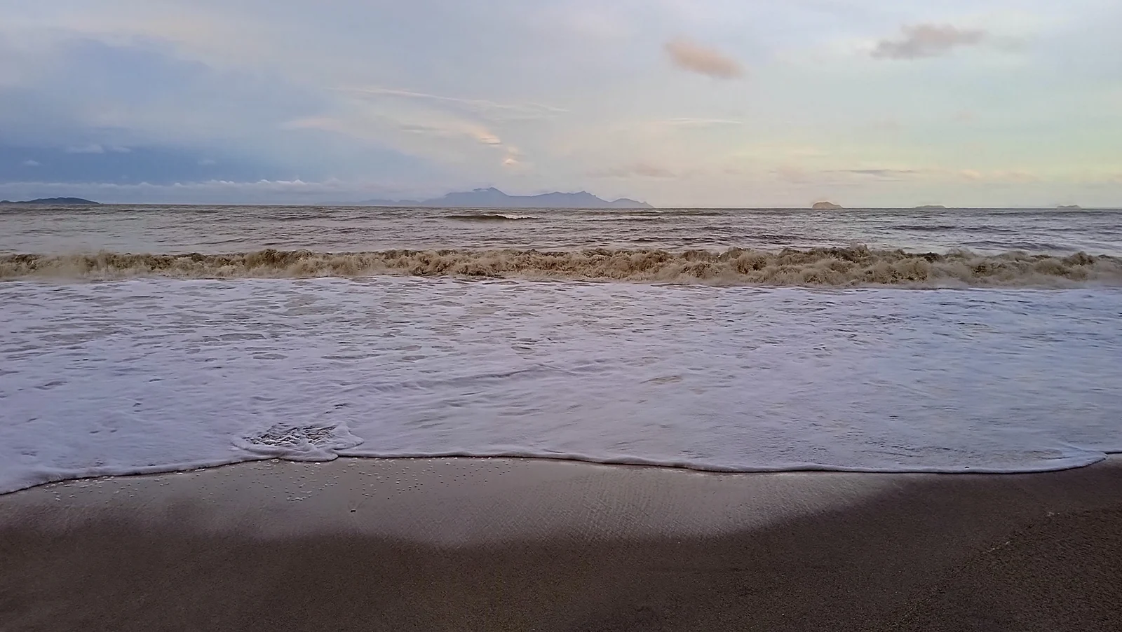 Waves and distant island silhouettes at Air Papan Beach, photographed by Wiki Farazi in December 2022